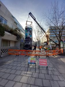 Cylindrical sign being lifted into place at Brunswick shopping centre